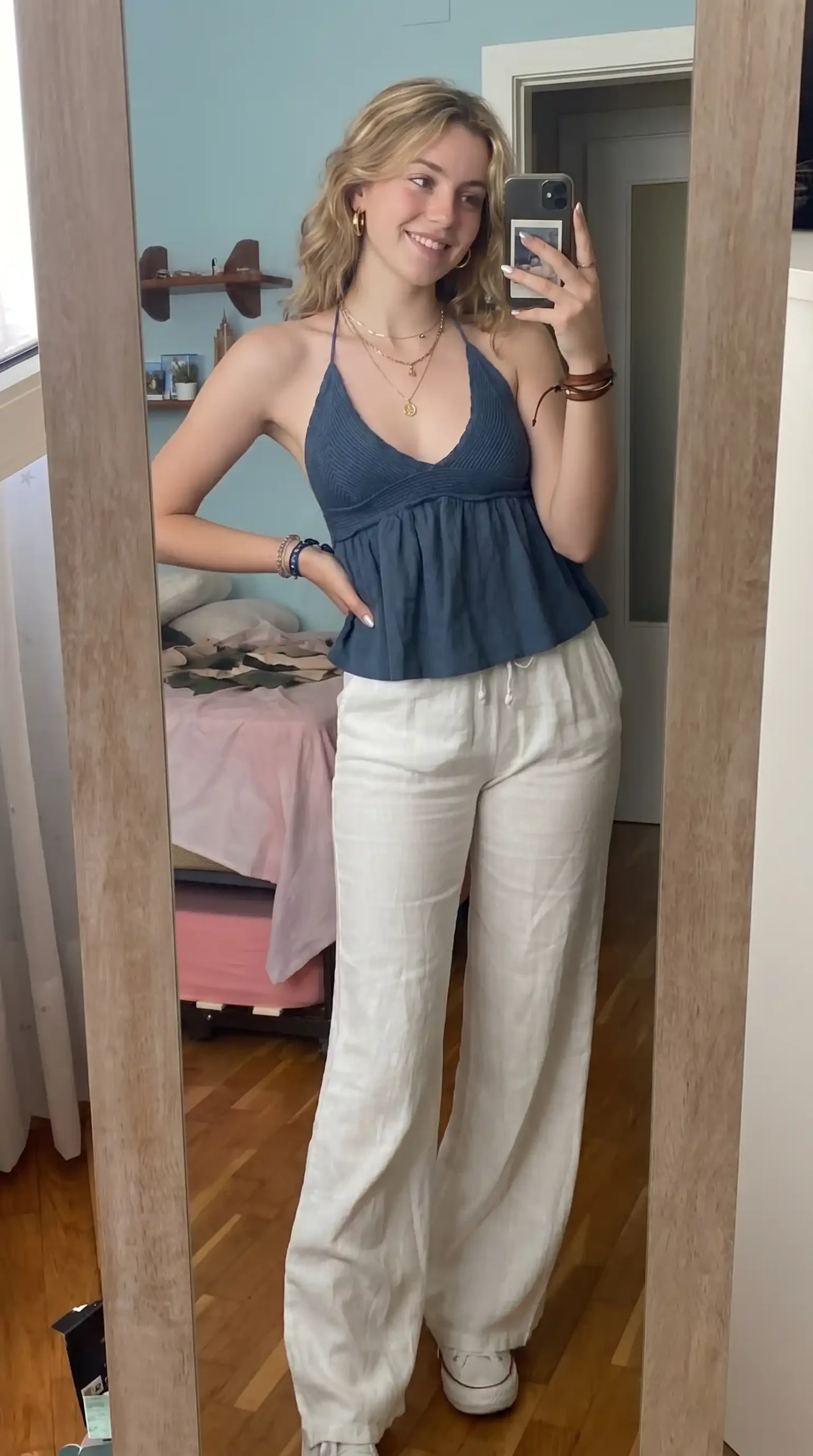 Woman wearing navy blue knit babydoll top with white linen pants at home