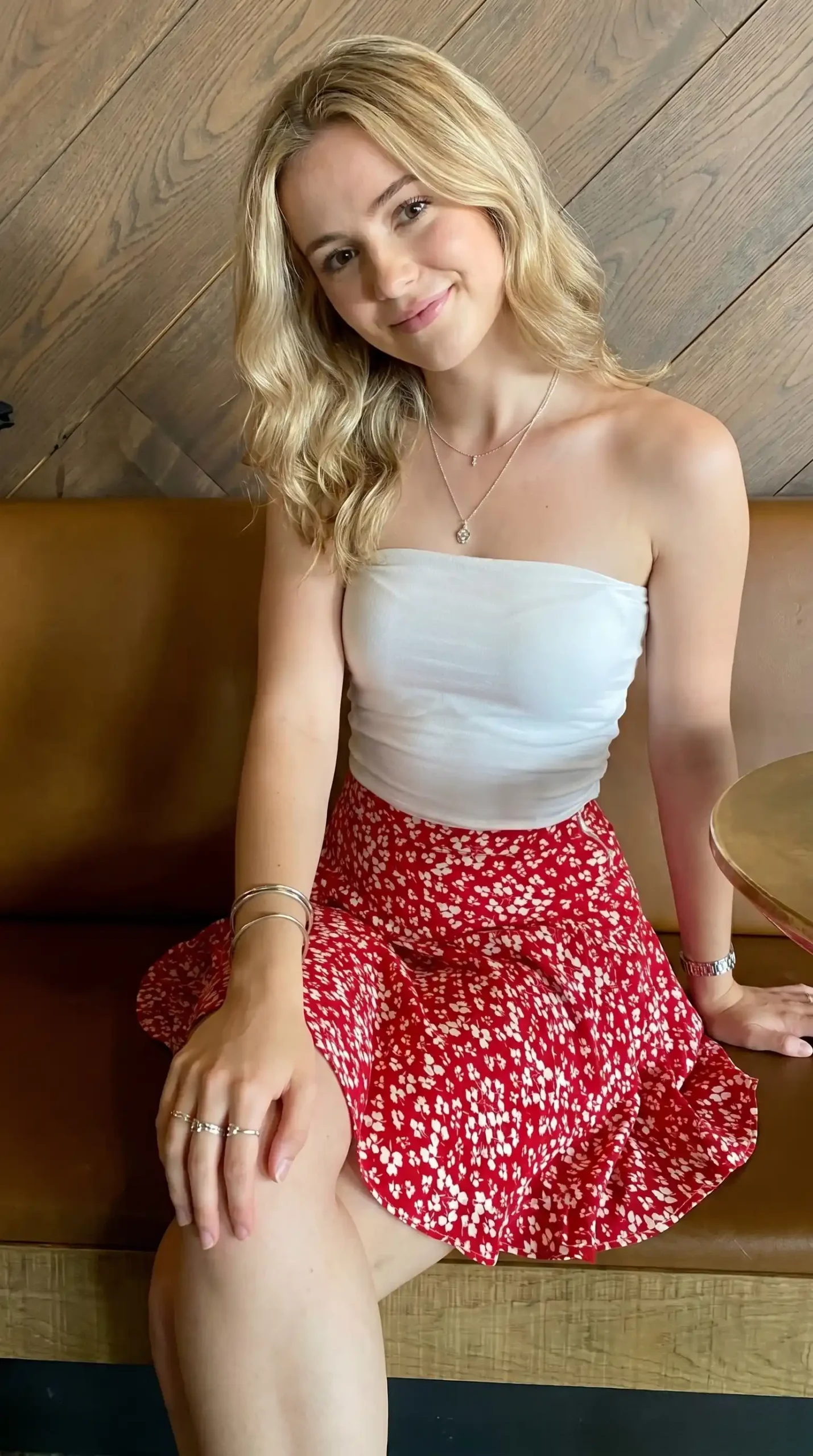 Woman wearing white tube top with red and white floral mini skirt indoors