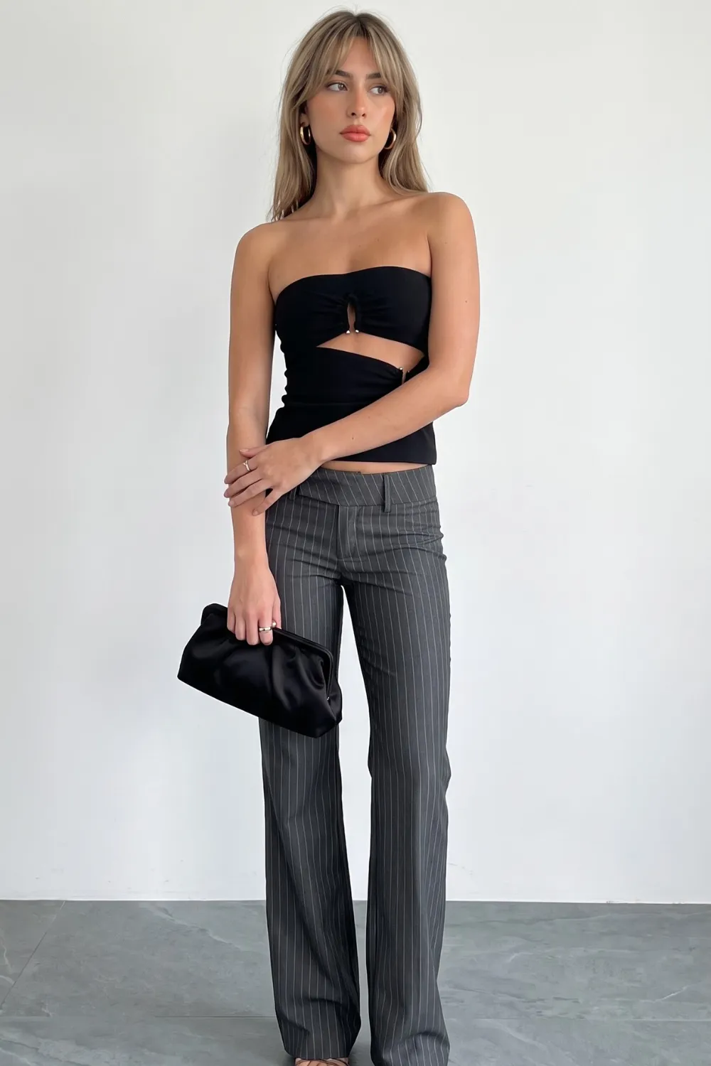 Woman in black cutout strapless top with grey pinstripe wide leg