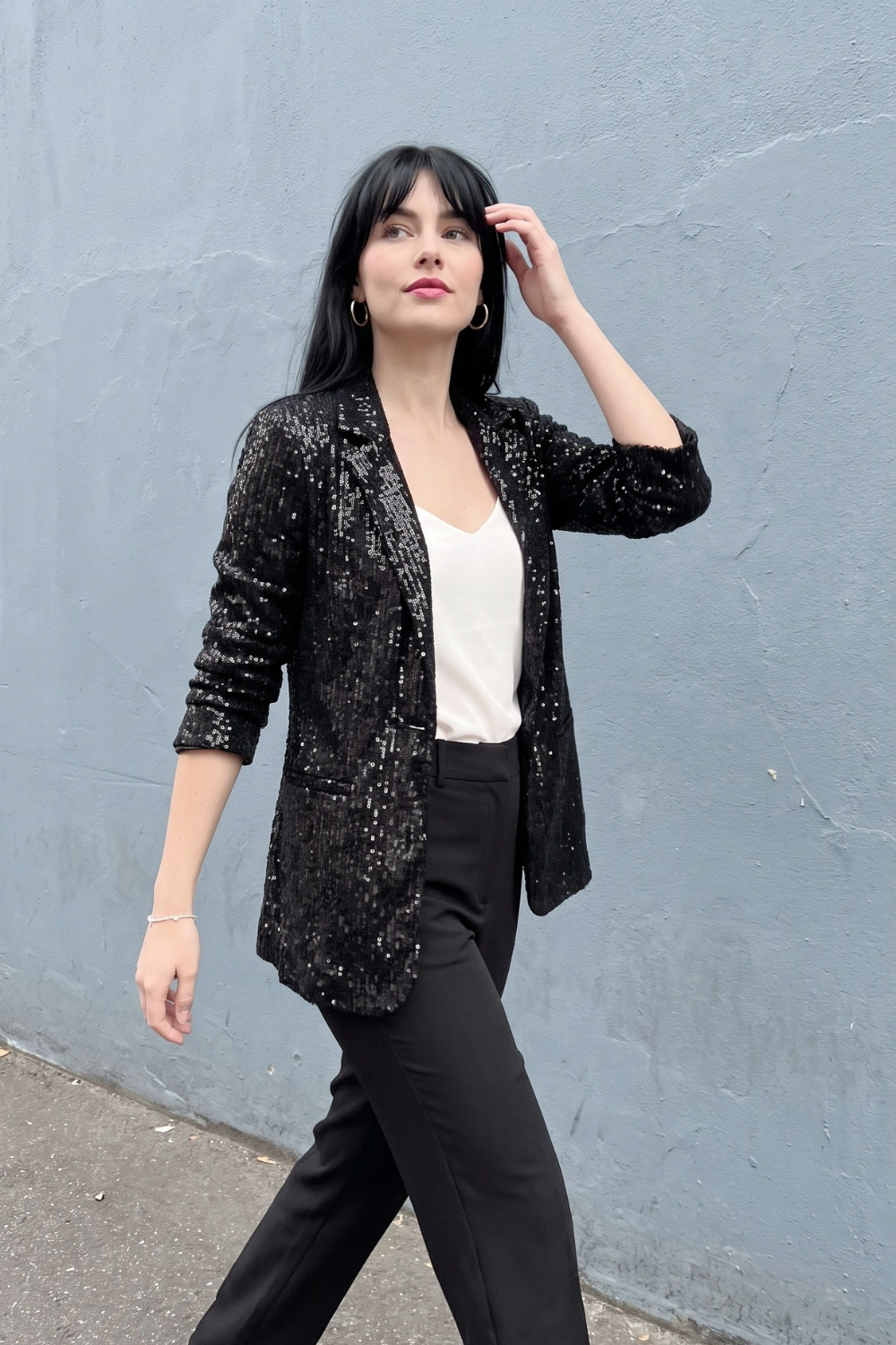 Woman in black sequin oversized blazer white satin cami top and black tailored trousers