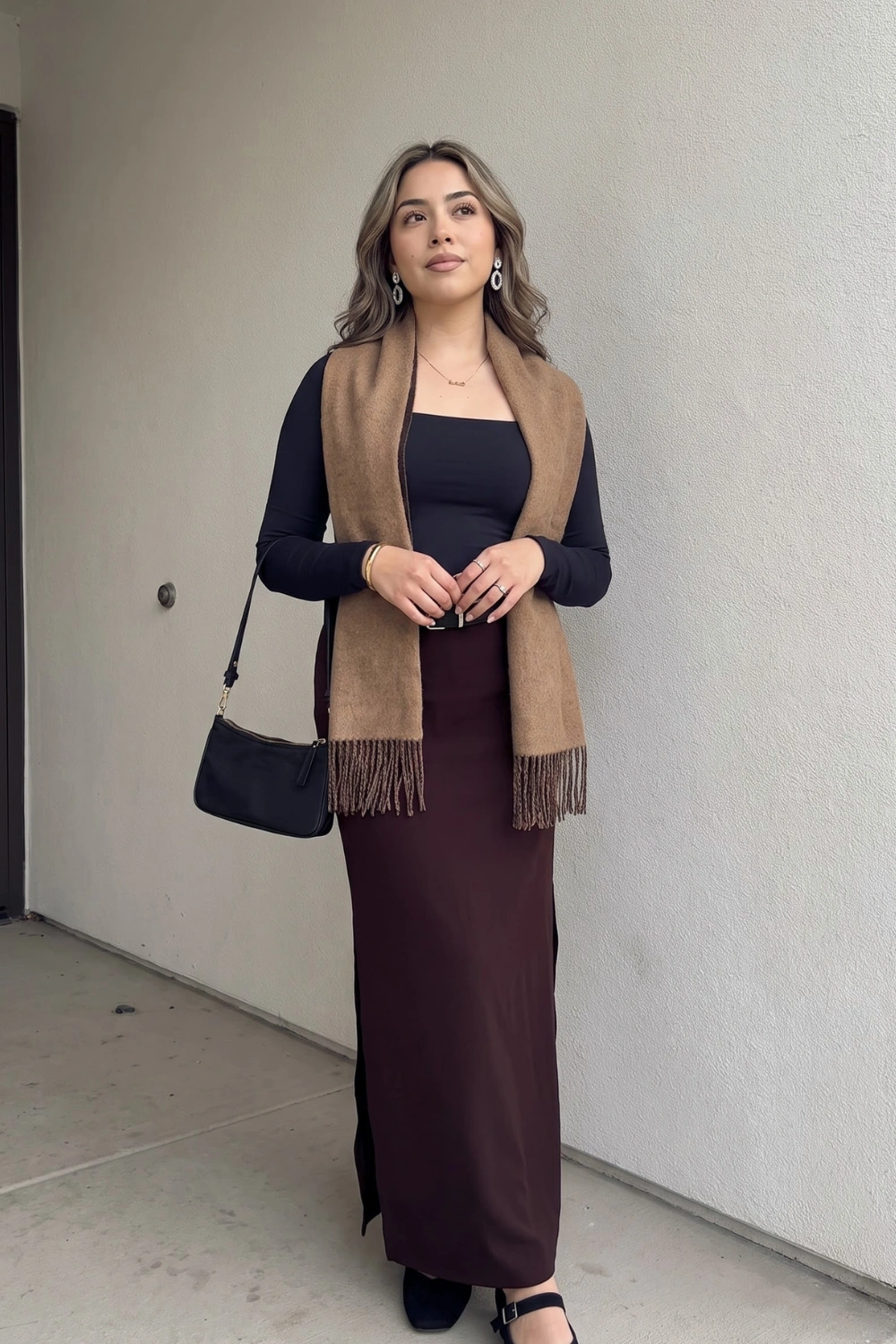 Woman in black long sleeve top dark chocolate brown satin maxi skirt and camel fringe scarf