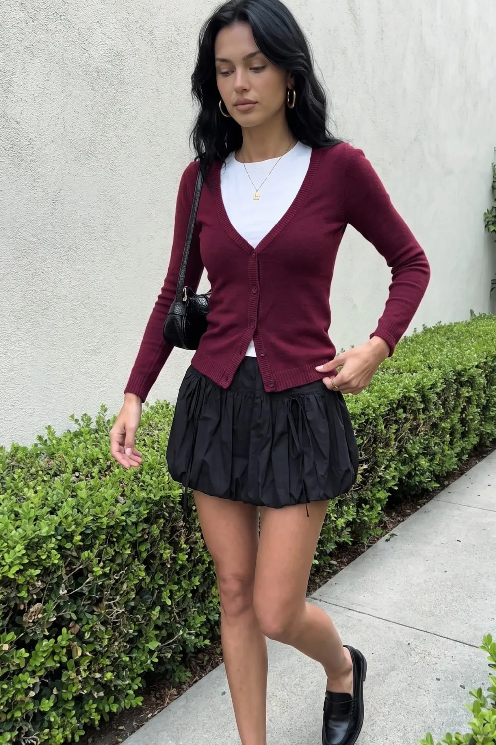 Woman in burgundy cardigan with white tee and black bubble mini skirt