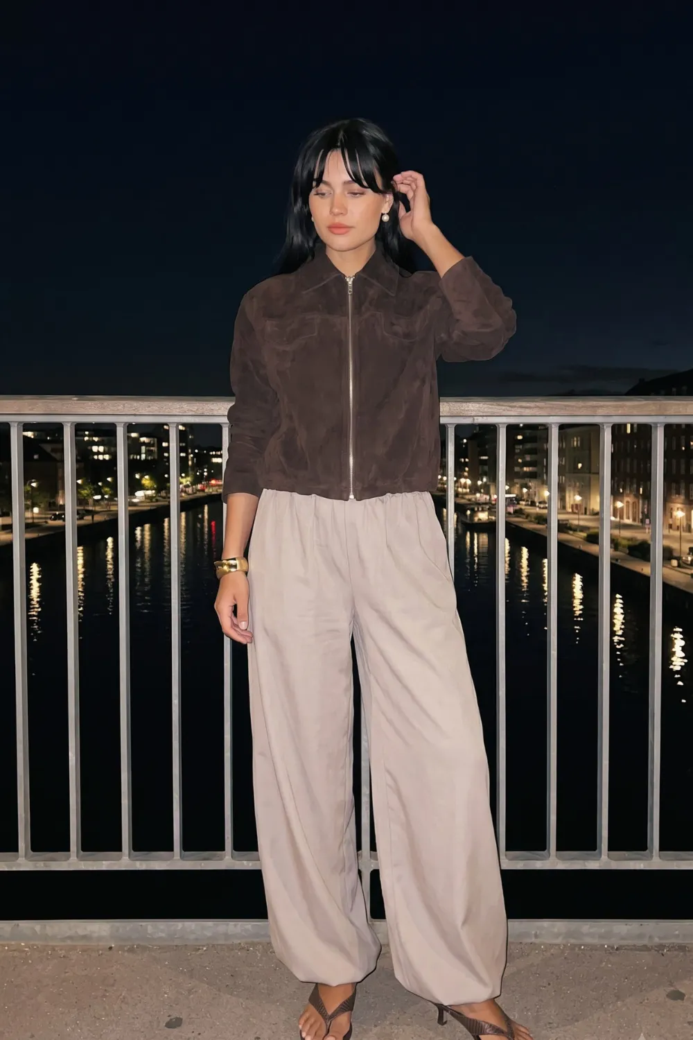 Woman in dark brown suede zip bomber jacket with beige wide leg parachute pants
