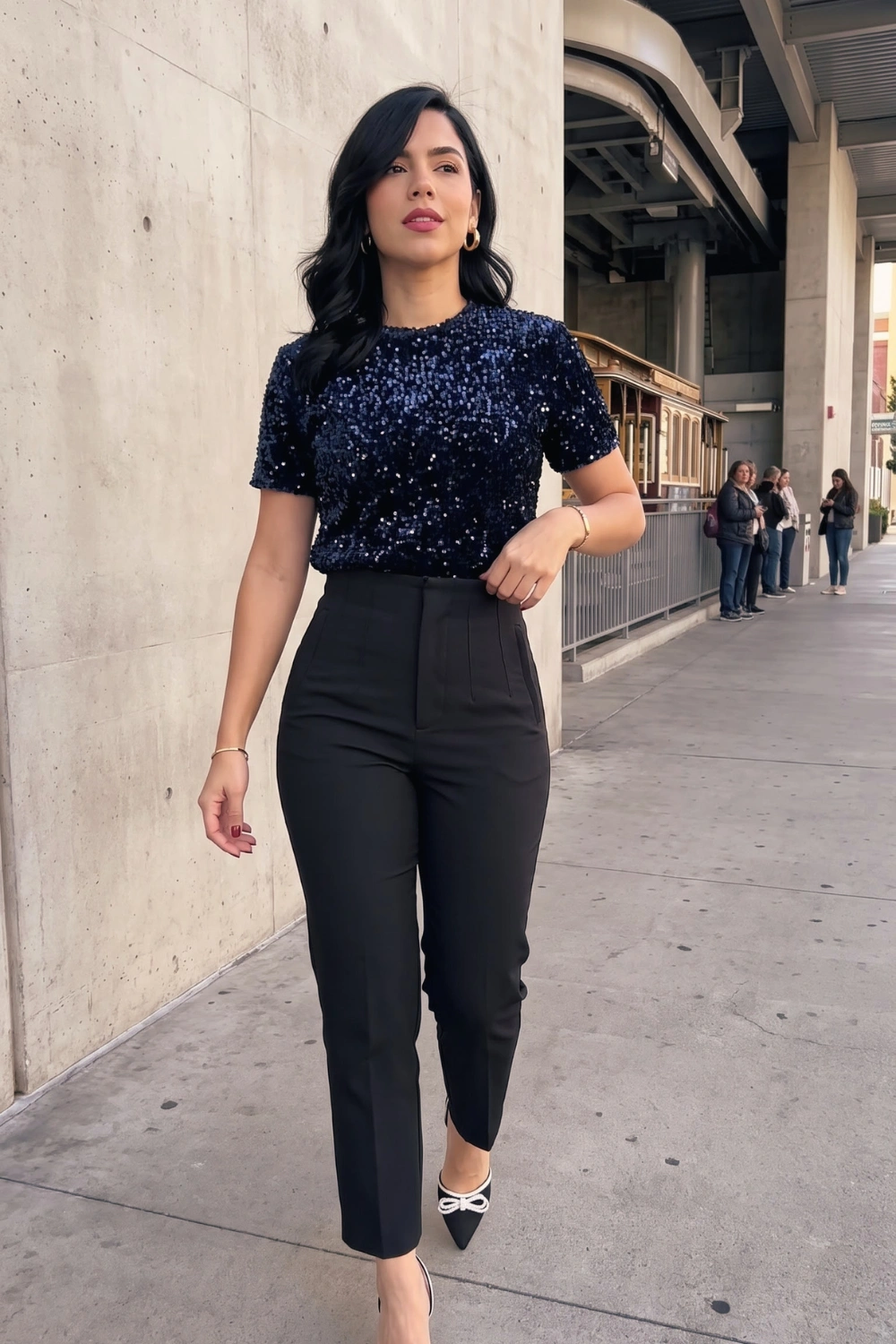 Woman in navy blue sequin short sleeve top and black high waist tailored trousers