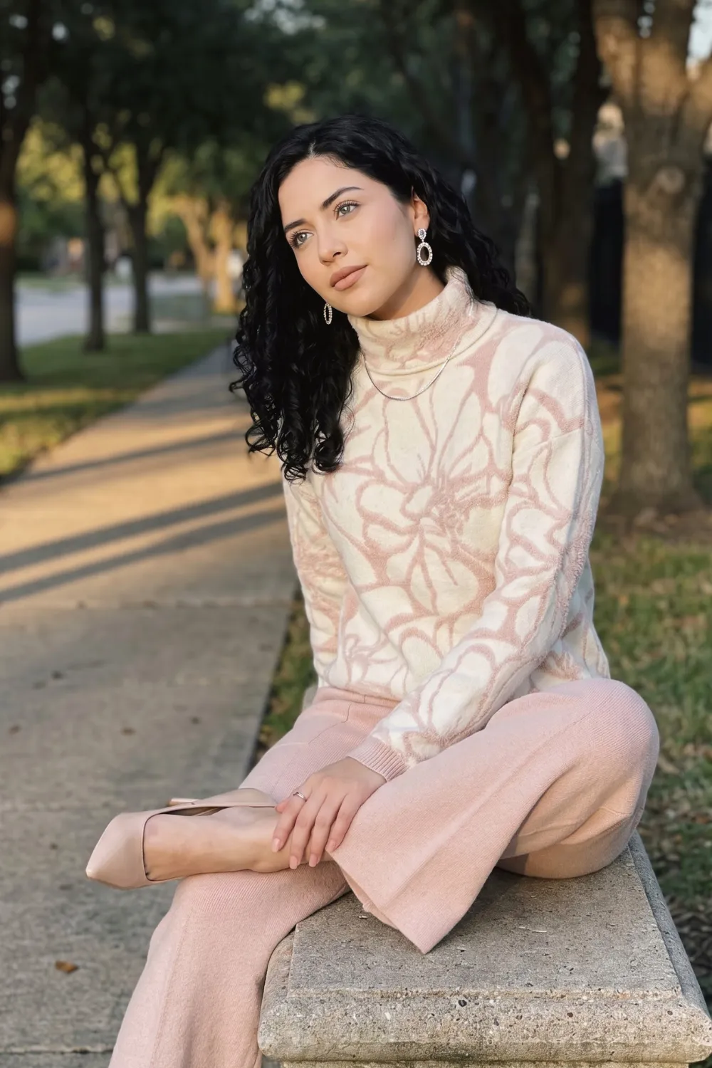 Woman in cream and pink floral turtleneck knit sweater with blush wide leg knit trousers