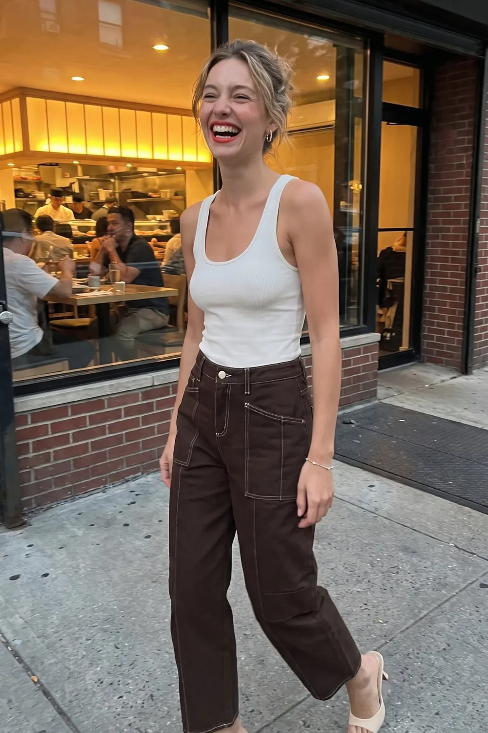 Woman in white ribbed tank top with dark brown contrast stitch barrel jeans and nude heels