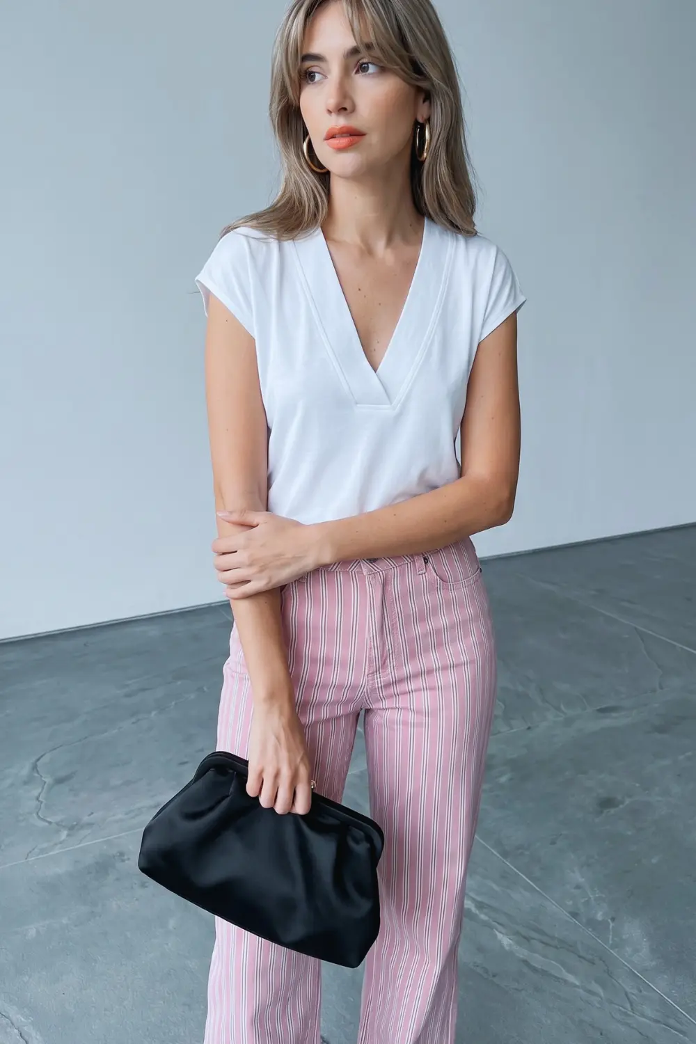 Woman in white v neck cap sleeve top and pink white stripe wide leg jeans